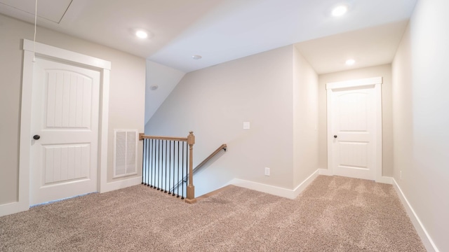 hallway featuring attic access, visible vents, carpet flooring, and an upstairs landing