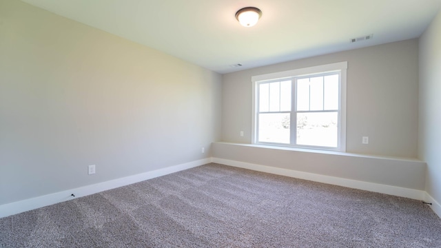 unfurnished room featuring carpet flooring, visible vents, and baseboards