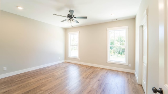 spare room with light wood-style floors, plenty of natural light, a ceiling fan, and baseboards