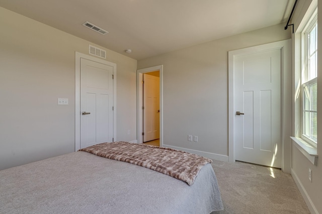 bedroom featuring visible vents, light carpet, and baseboards