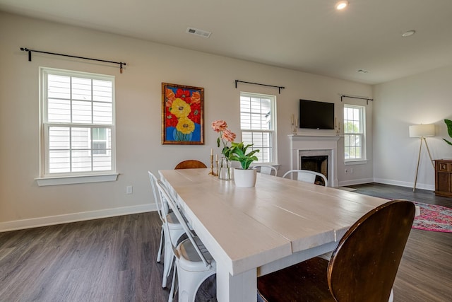 dining space featuring baseboards, a fireplace, visible vents, and dark wood-style flooring