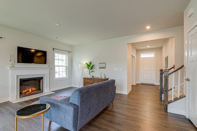 living room with dark wood-type flooring, a fireplace, baseboards, and stairs