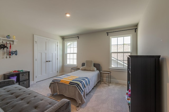 bedroom with light carpet, multiple windows, baseboards, and a closet