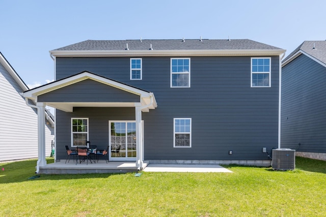 rear view of house with a patio area, a shingled roof, cooling unit, and a yard