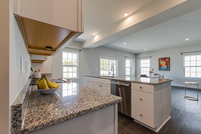 kitchen featuring baseboards, dark wood finished floors, dishwasher, white cabinetry, and a sink