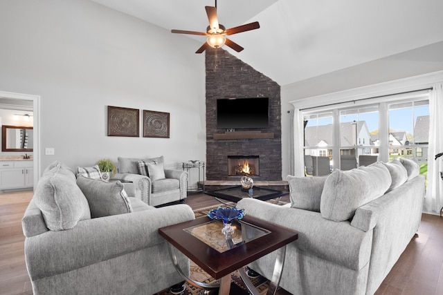 living area featuring ceiling fan, high vaulted ceiling, a fireplace, and wood finished floors