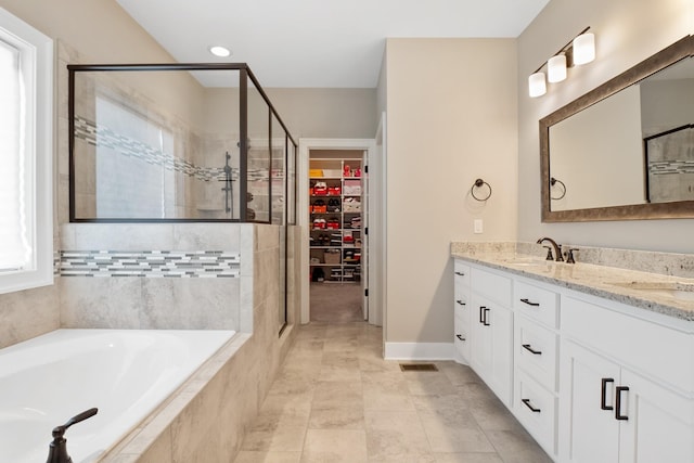 bathroom with a bath, a sink, a walk in closet, and a shower stall