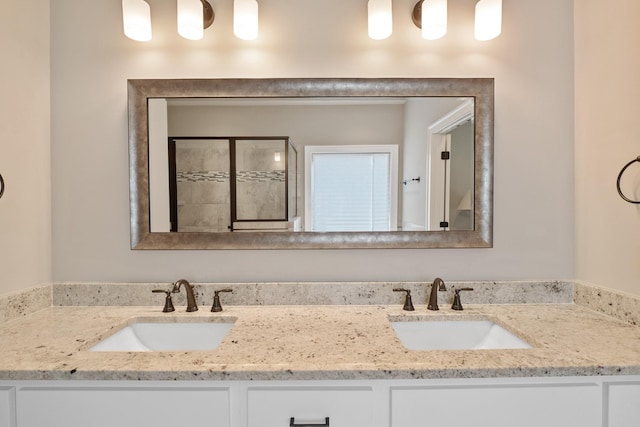 bathroom with a sink, a tile shower, and double vanity