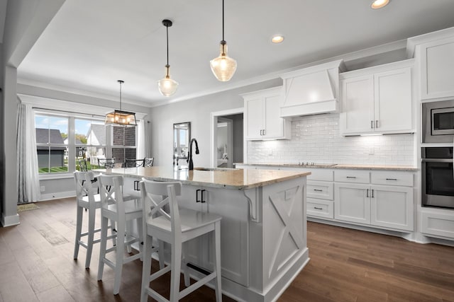 kitchen featuring tasteful backsplash, custom range hood, appliances with stainless steel finishes, crown molding, and a sink