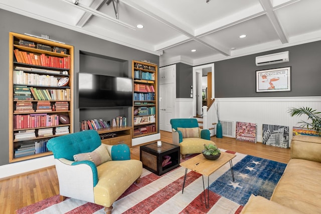 living area featuring a wainscoted wall, a wall unit AC, visible vents, wood finished floors, and coffered ceiling