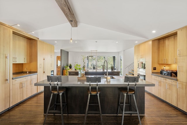 kitchen featuring lofted ceiling with beams, a kitchen bar, modern cabinets, and light brown cabinetry