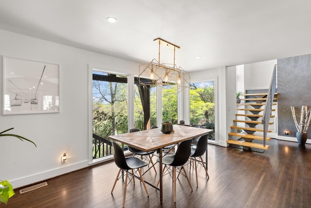 dining area with visible vents, wood finished floors, a chandelier, baseboards, and stairs