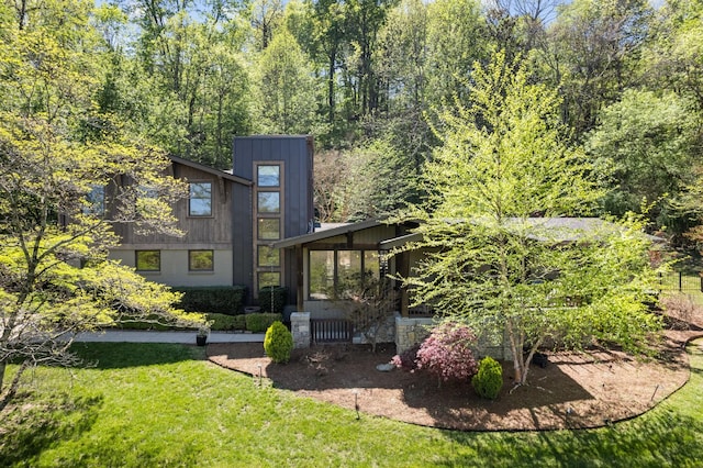 back of property featuring a sunroom and a lawn