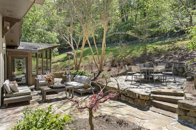 view of patio / terrace featuring outdoor lounge area, fence, and a forest view