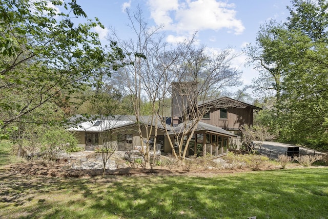 back of house featuring a lawn and a sunroom