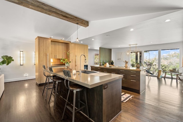 kitchen featuring a breakfast bar, a large island, light countertops, lofted ceiling with beams, and dark wood-type flooring