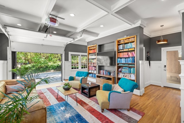 living area featuring a garage, coffered ceiling, wainscoting, wood finished floors, and beam ceiling