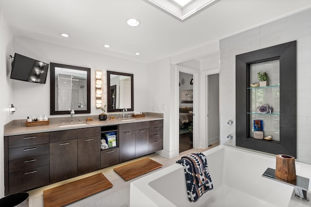 full bath featuring double vanity, a skylight, a bathing tub, and a sink