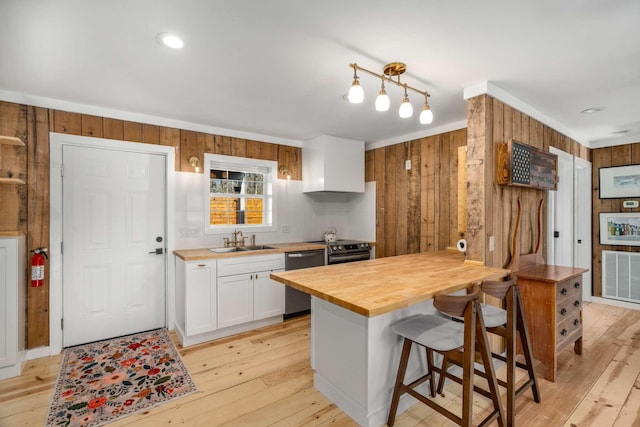 kitchen featuring visible vents, wood walls, a sink, wood counters, and dishwasher