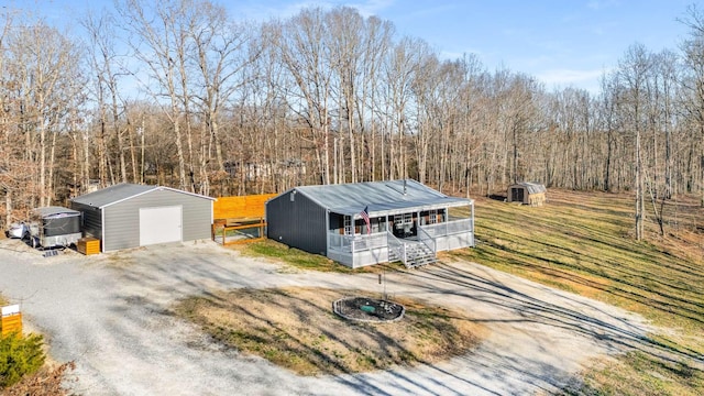 view of front of home with dirt driveway, a storage unit, covered porch, a garage, and an outdoor structure