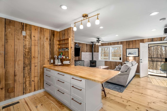 kitchen with a wood stove, visible vents, wood walls, and wood counters