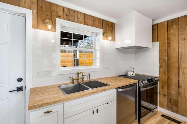 kitchen featuring dishwasher, electric range oven, wood counters, a sink, and backsplash