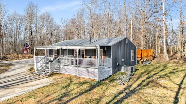 view of front of home featuring driveway, central AC unit, a porch, metal roof, and a front lawn