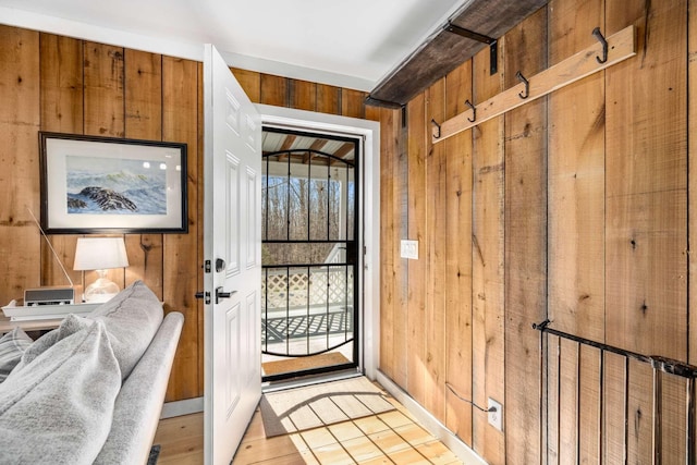 doorway with wood walls and light wood-style floors