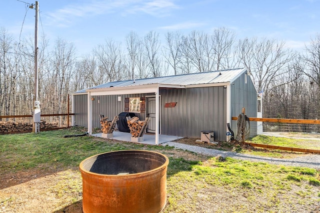 view of outbuilding featuring an outdoor fire pit, fence, and an outdoor structure