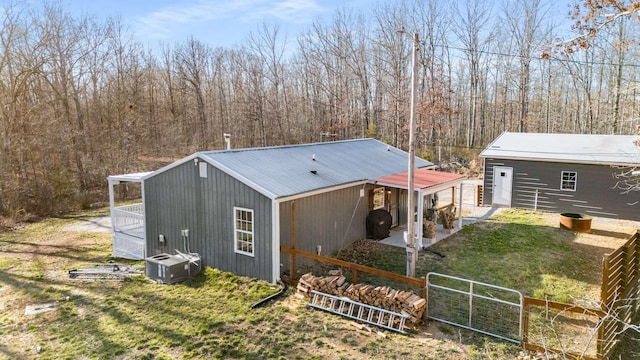 rear view of property with central AC unit, an outdoor structure, fence, and a gate