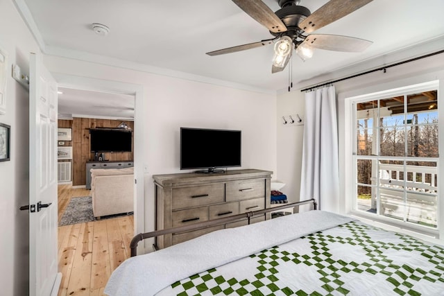 bedroom with a ceiling fan, wood walls, light wood-style flooring, and crown molding