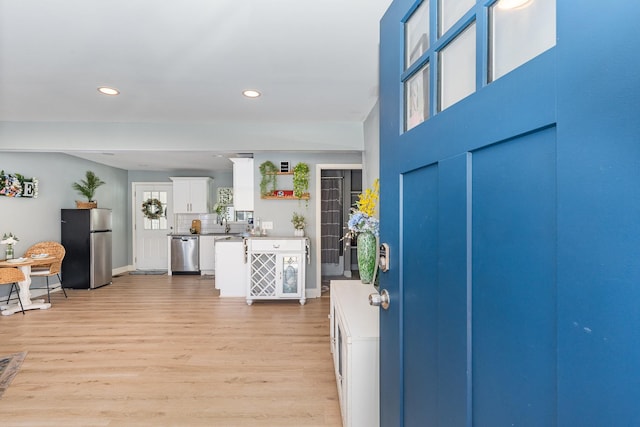 foyer featuring light wood-style floors, baseboards, and recessed lighting