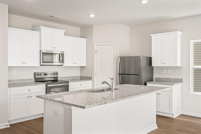 kitchen featuring an island with sink, dark wood-type flooring, stainless steel appliances, and a sink