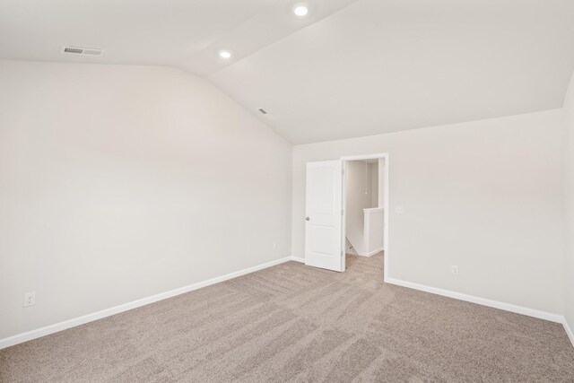 carpeted empty room featuring lofted ceiling, visible vents, baseboards, and recessed lighting