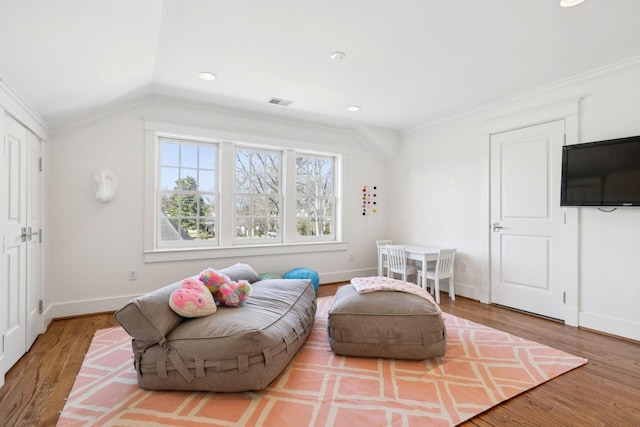 living area with lofted ceiling, wood finished floors, visible vents, and baseboards