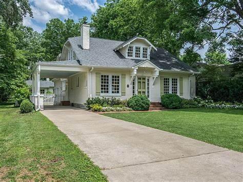 view of front of house with a carport, concrete driveway, a front lawn, and a chimney