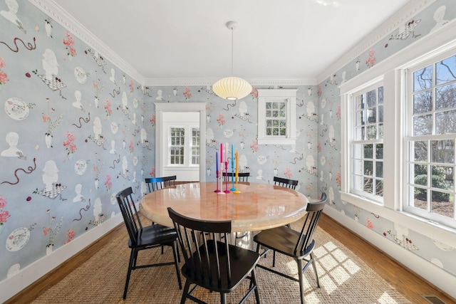 dining area with crown molding, visible vents, light wood-type flooring, baseboards, and wallpapered walls