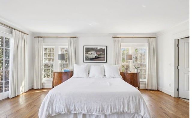 bedroom featuring crown molding, wood finished floors, and baseboards