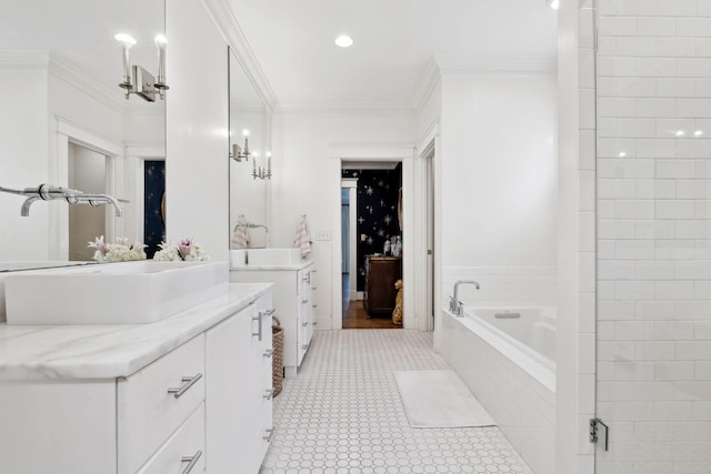 bathroom featuring ornamental molding, two vanities, a sink, and a garden tub