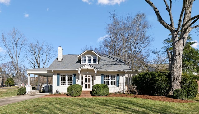 view of front of property featuring concrete driveway, a chimney, an attached carport, a front yard, and brick siding