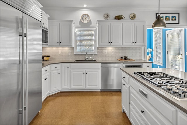 kitchen with crown molding, white cabinets, a sink, and built in appliances