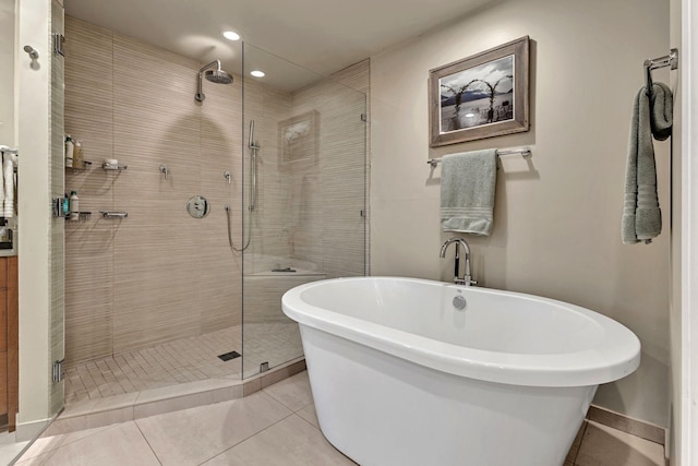 bathroom featuring recessed lighting, a freestanding bath, a shower stall, baseboards, and tile patterned floors