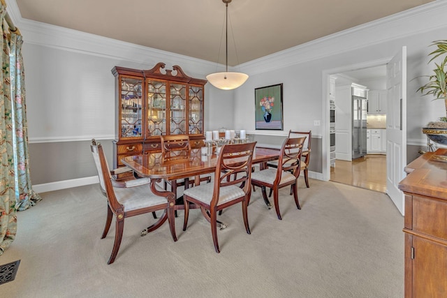 dining area featuring ornamental molding, light colored carpet, and baseboards