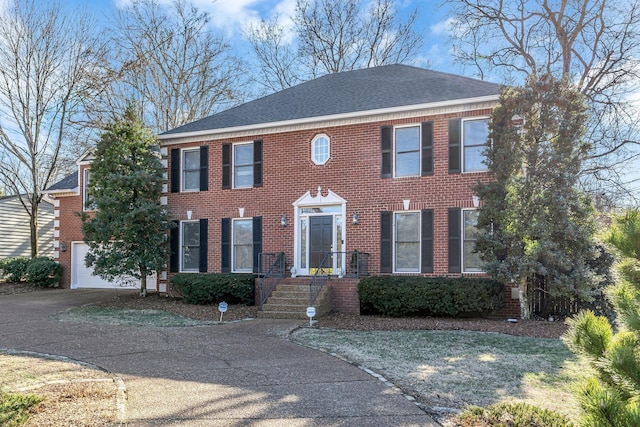 view of front of home featuring a garage, driveway, brick siding, and a shingled roof