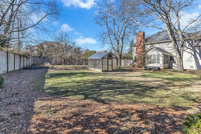 view of yard featuring a fenced backyard, a greenhouse, and an outdoor structure