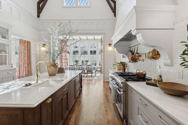 kitchen featuring a towering ceiling, plenty of natural light, range with two ovens, and a sink