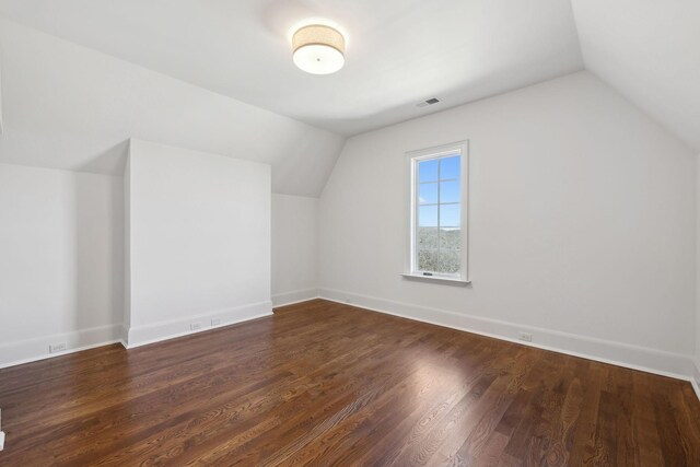 additional living space featuring vaulted ceiling, wood finished floors, visible vents, and baseboards