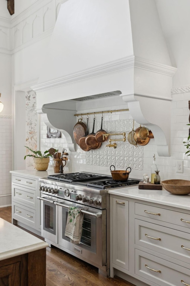 kitchen featuring dark wood-style floors, double oven range, light countertops, and backsplash