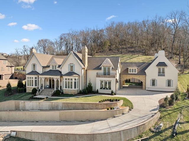 view of front of property featuring concrete driveway, french doors, and a front lawn