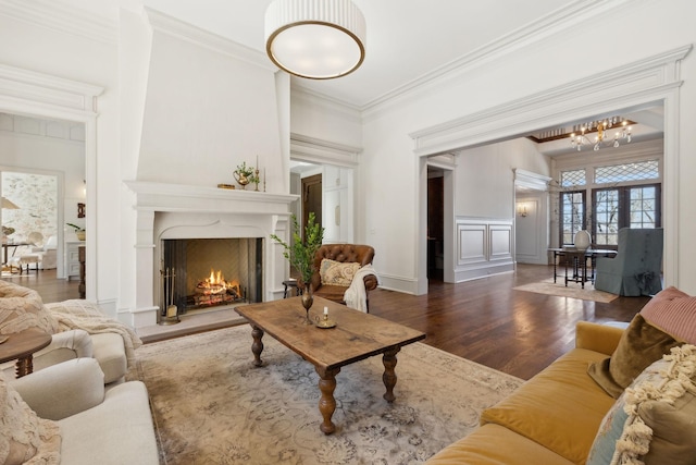 living area with a decorative wall, a wainscoted wall, a premium fireplace, wood finished floors, and crown molding